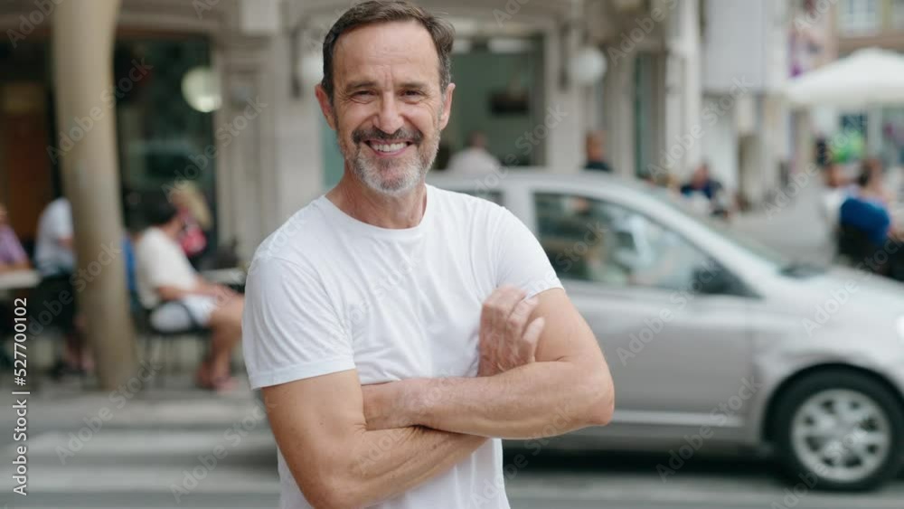 Middle age man standing with arms crossed gesture at street Middle age man standing with arms crossed gesture at street