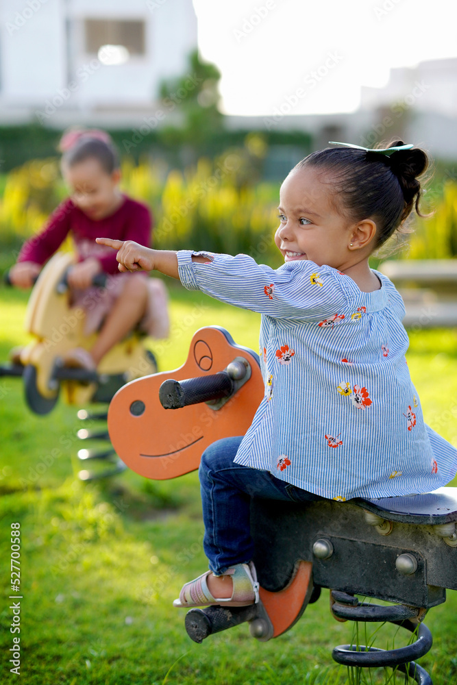 Φωτογραφία Niña feliz en un caballo de madera jugando en el parque disfrutando y viviendo a