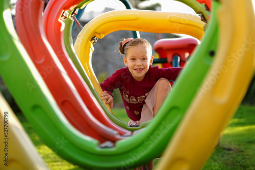 Niña hermosa rubia latina feliz alegre jugando divertida cruzando un área de juegos en el parque al exterior al aire libre en un hermoso día soleado