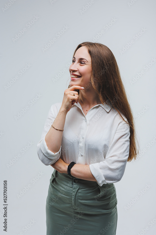 a woman wears a white blouse and skirt on a gray background. emotions on a woman's face. Elegant look. positive woman. Model in casual clothes. Summer, spring or autumn street look. a woman wears a white blouse and skirt on a gray background. emotions on a woman's face. Elegant look. positive woman. Model in casual clothes. Summer, spring or autumn street look.