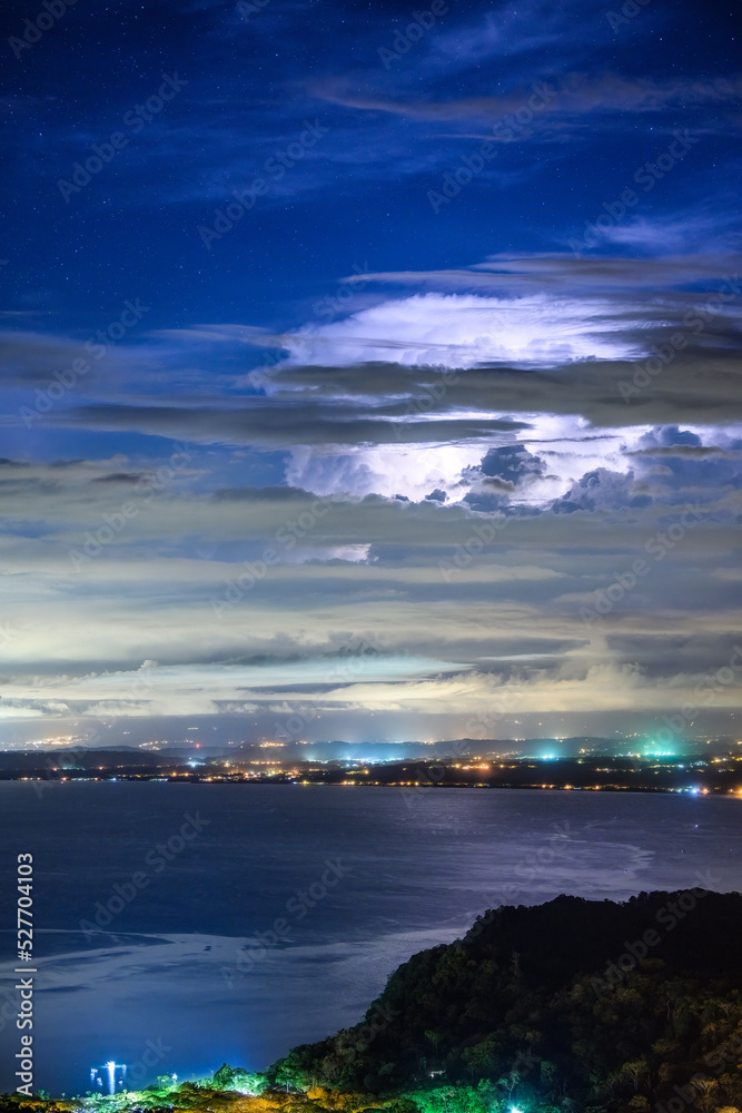 Stars appear as lightning illuminates massive cumulus clouds in a thunderstorm above Puntarenas, Costa Rica