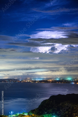 Fototapeta Naklejka Na Ścianę i Meble -  Stars appear as lightning illuminates massive cumulus clouds in a thunderstorm above Puntarenas, Costa Rica