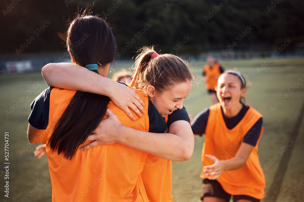 Naklejka premium Happy soccer player embracing her teammate after scoring a goal during match.