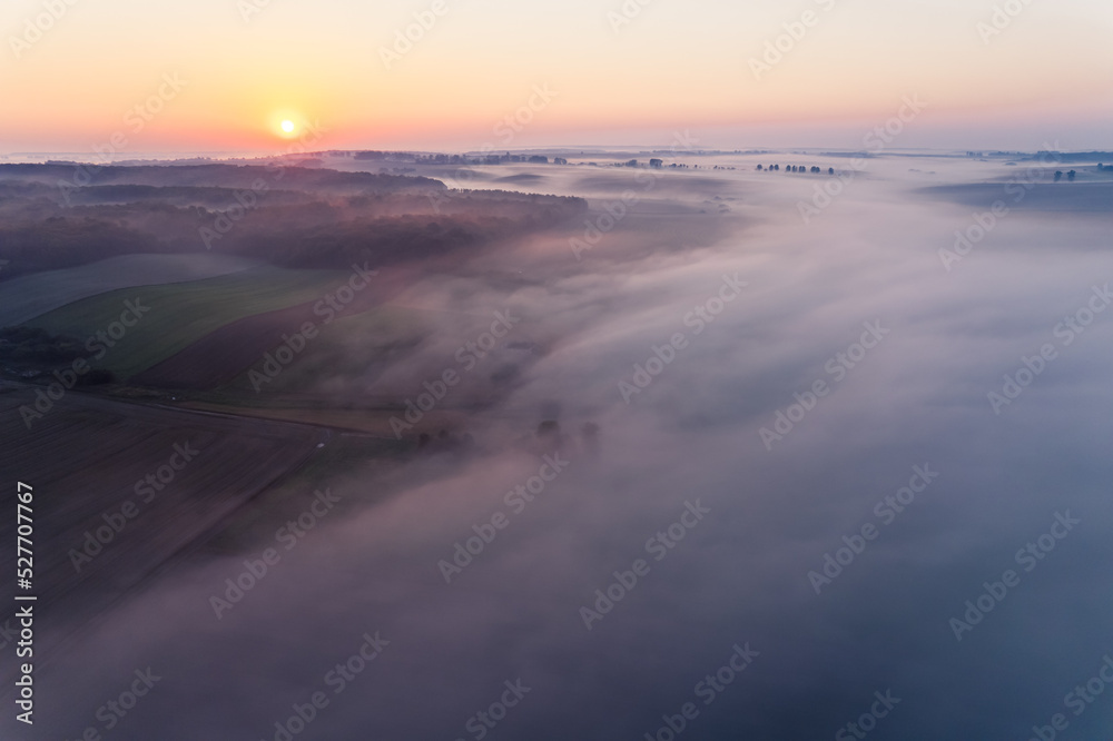 Thick fog spreading over green farm fields in Roztocze Poland during colorful sunrise. Morning landscape. Horizontal shot. High quality photo
