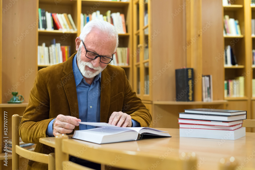 Senior man reading book in the library