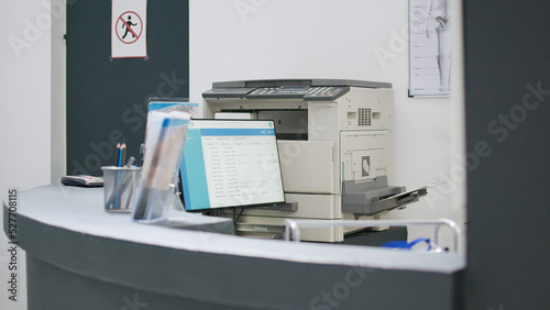 Hospital reception counter with medical appointments on computer to help patients with healthcare insurance. Empty registration desk used to give support and fill in checkup papers.