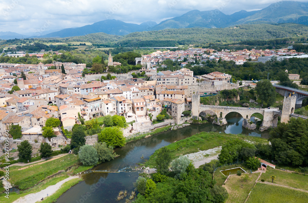 Panoramic view from drone of fortified village of Besalu with Fluvia river and medieval arched bridge, Spain.