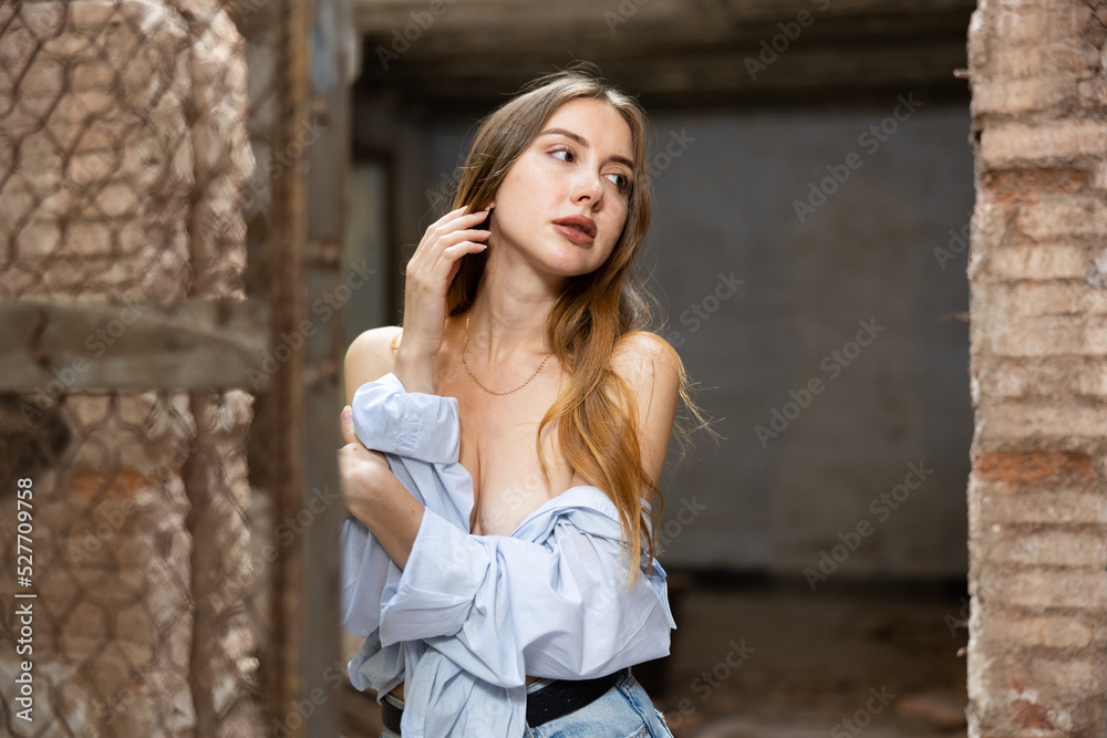 Tempting caucasian woman with naked shoulders and breast posing in derelict house.