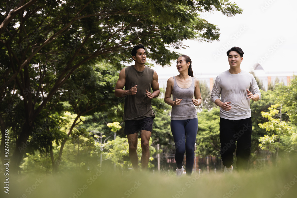 Asian young man and woman jogging together in green park. Concept for healthy lifestyle and oudoor life.