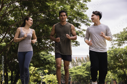 Asian young man and woman jogging together in green park. Concept for healthy lifestyle and oudoor life.