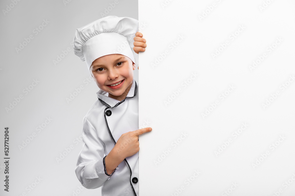 cooking, culinary and profession concept - happy smiling little boy in chef's toque and jacket with white board over grey background cooking, culinary and profession concept - happy smiling little boy in chef's toque and jacket with white board over grey background