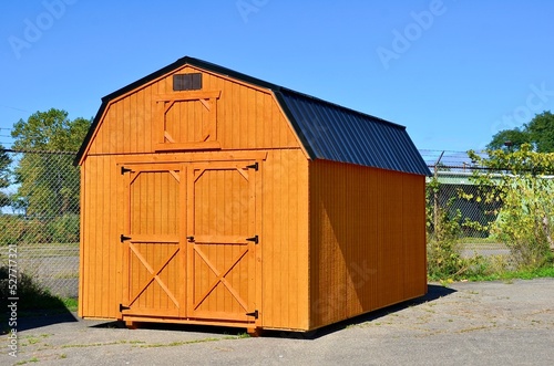 American style wooded shed. A shed is typically simple, single-story roofed structure in a back garden or on an allotment that is used for storage, hobbies, or as a workshop. Exterior view photo