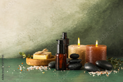 Spa composition with burning candles and cosmetics on color background