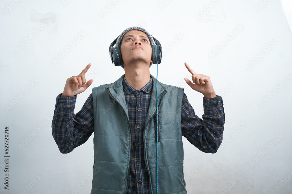 asian young man wearing dark blue vest and beanie wearing headphones, isolated on white background quirky and trendy while listening to music asian young man wearing dark blue vest and beanie wearing headphones, isolated on white background quirky and trendy while listening to music
