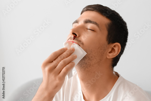 Young man wiping nosebleed ...