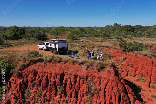 Aerial landscape view of happy Australian family waving hellon beside a car and caravan