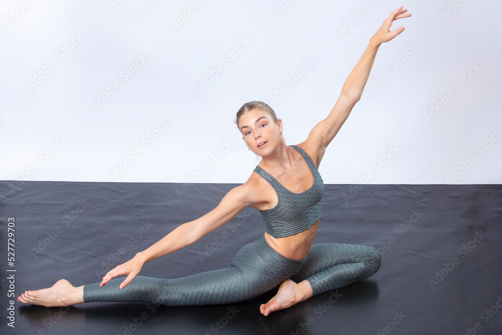 Young woman in yoga moves in Connecticut studio, white background.