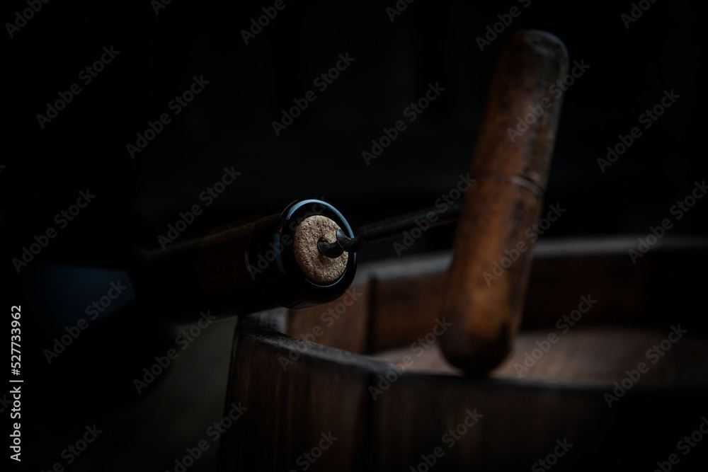 Obraz premium A bottle of wine is opened with a corkscrew. A corkscrew with a wooden handle.Out of focus.Selective focus.