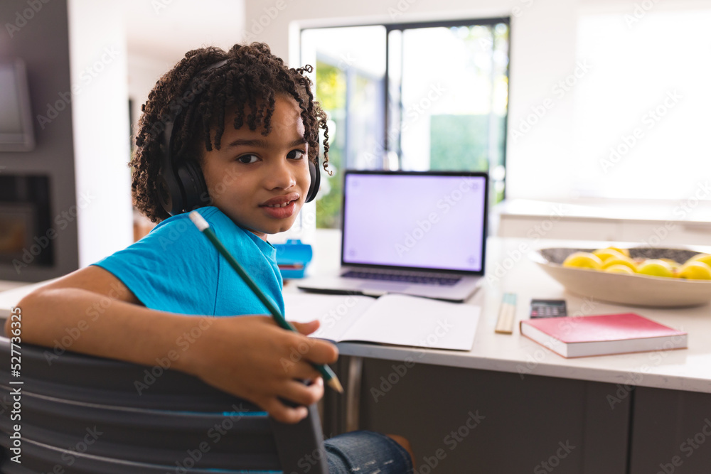 Hispanic boy sitting on chair looking back over shoulder while studying at home Hispanic boy sitting on chair looking back over shoulder while studying at home