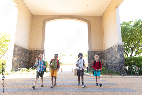 Slika na platnu Full length of smiling multiracial elementary schoolboys with backpack entering