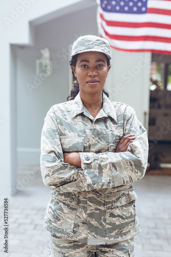 Portrait of confident female mid adult african american soldier in uniform standing outside house