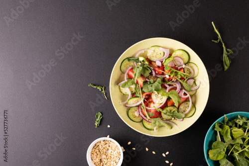 Overhead view of healthy salad in bowl on black background, copy space