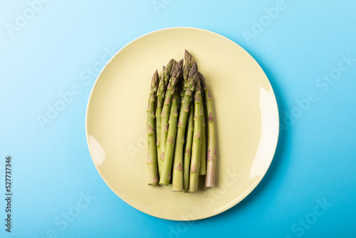 Directly above view of fresh asparagus in white plate on blue background