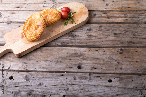 High angle view of pies with tomatoes and rosemary on serving board at table with blank space