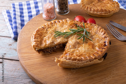 High angle view of baked stuffed pies with rosemary served on serving board at table