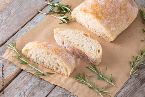 High angle view of bread with rosemary over brown wax paper at table