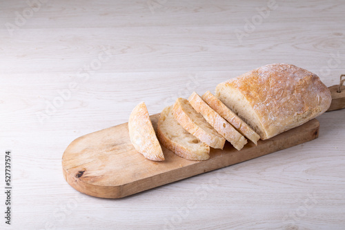 High angle close-up of sliced bread loaf on wooden serving board at table