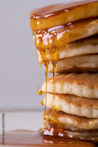 Close-up of tempting stacked pancakes with dripping syrup against gray background
