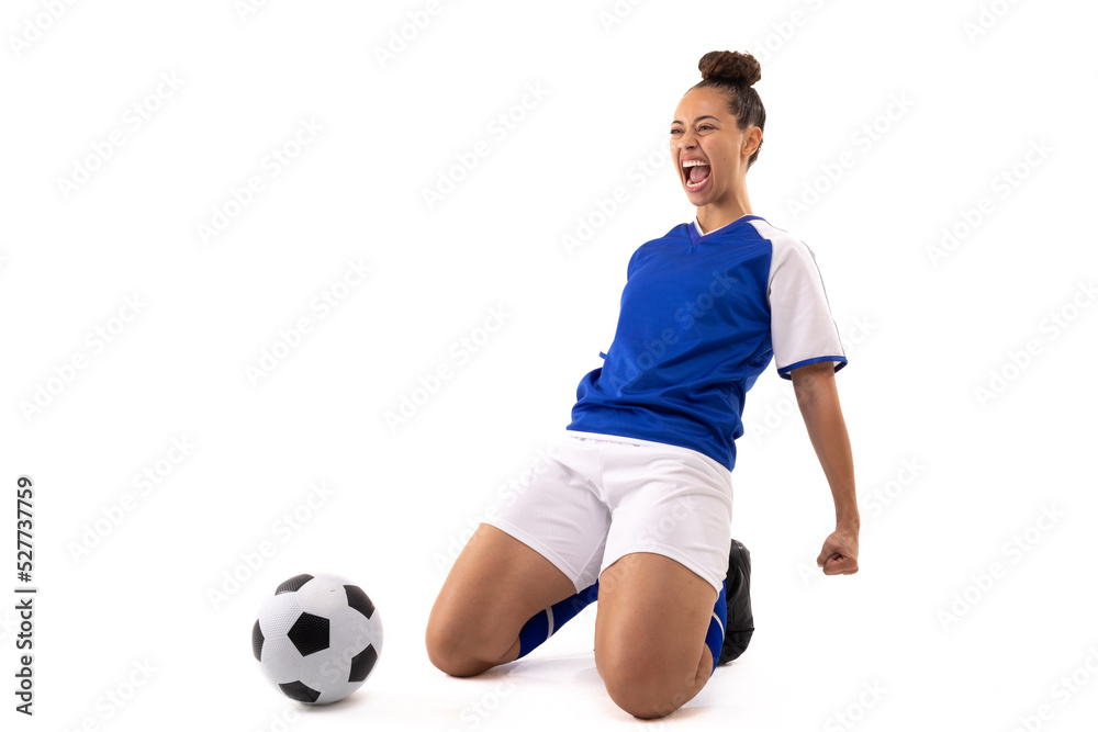 Biracial young female soccer player shouting while kneeling by soccer ball against white background