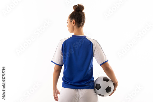 Rear view of biracial young female soccer player with soccer ball standing over white background