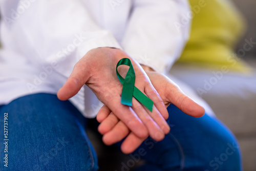 Midsection of mature caucasian female doctor showing mental health awareness ribbon
