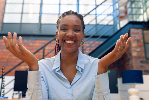 Portrait of cheerful african american young businesswoman gesturing while sitting in modern office