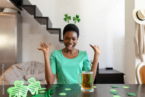 Excited african american woman shouting while looking at beer mug on table