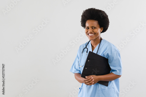 Portrait of happy african american mid adult doctor with clipboard over white background, copy space