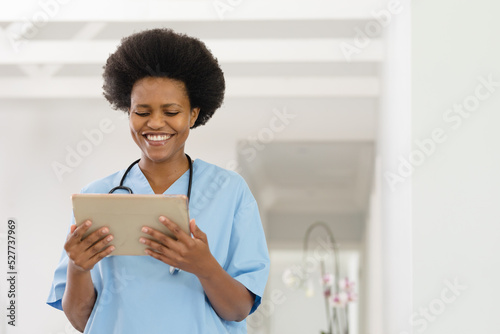 Happy african american mid adult female doctor using digital tablet in hospital