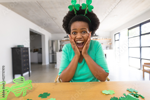 Portrait of surprised african american mid adult woman in shamrock headband at home