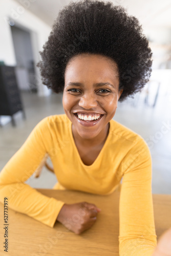 Portrait of happy african american mid adult female freelancer with afro hairstyle at home office