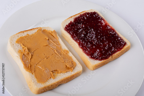 Close-up of open face peanut butter and jelly sandwich in plate on white background