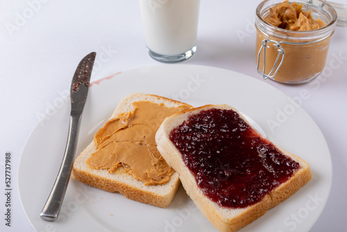 Close-up of open face peanut butter and jelly sandwich in plate by milk glass and jar on table