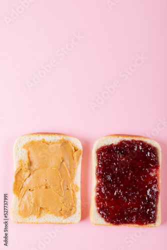 Directly above shot of open face peanut butter and jelly sandwich on pink background with copy space