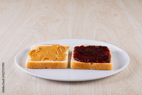 Close-up of bread slices with peanut butter and preserves served in plate on wooden table