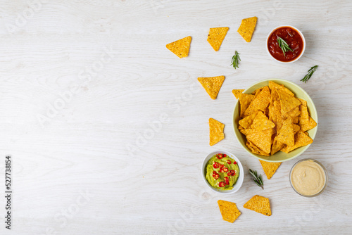 Overhead view of various dipping sauce served with nacho chips in bowl on table with empty space