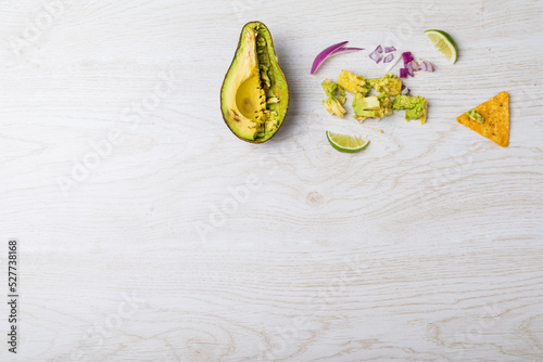 Overhead view of halved avocado and ingredients on table with empty space