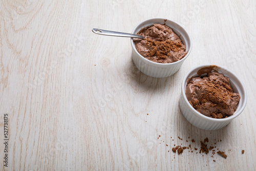 Chocolate mousse with cocoa powder and spoons served in ramekin bowls on table with blank space photo