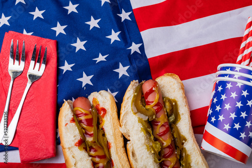 Overhead view of hot dogs with jalapeno served on american flag with fork and disposable cups