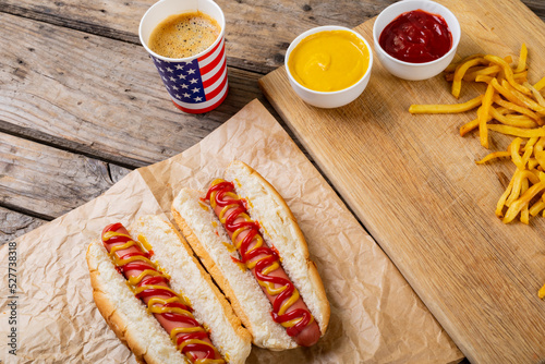 High angle view of hot dogs with french fries and sauces by drink on table